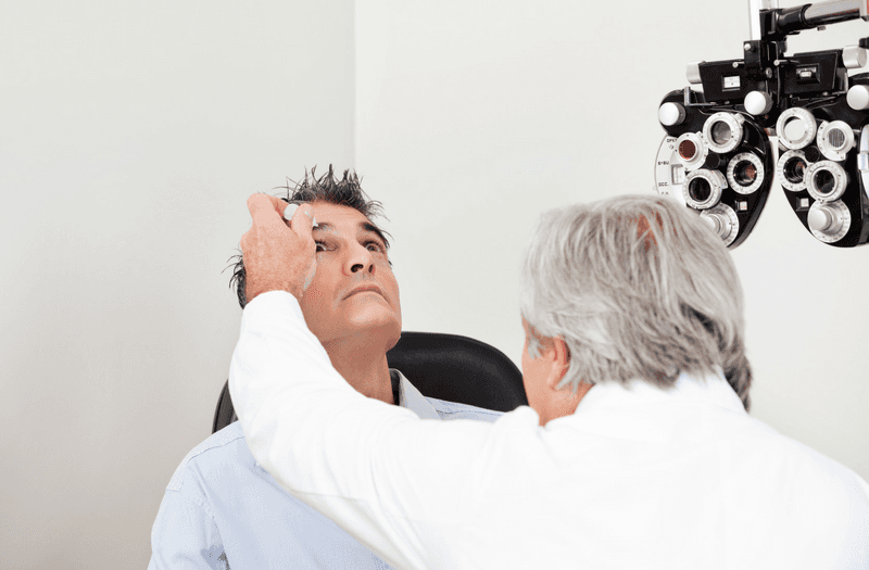 doctor administering eye drops to adult patient